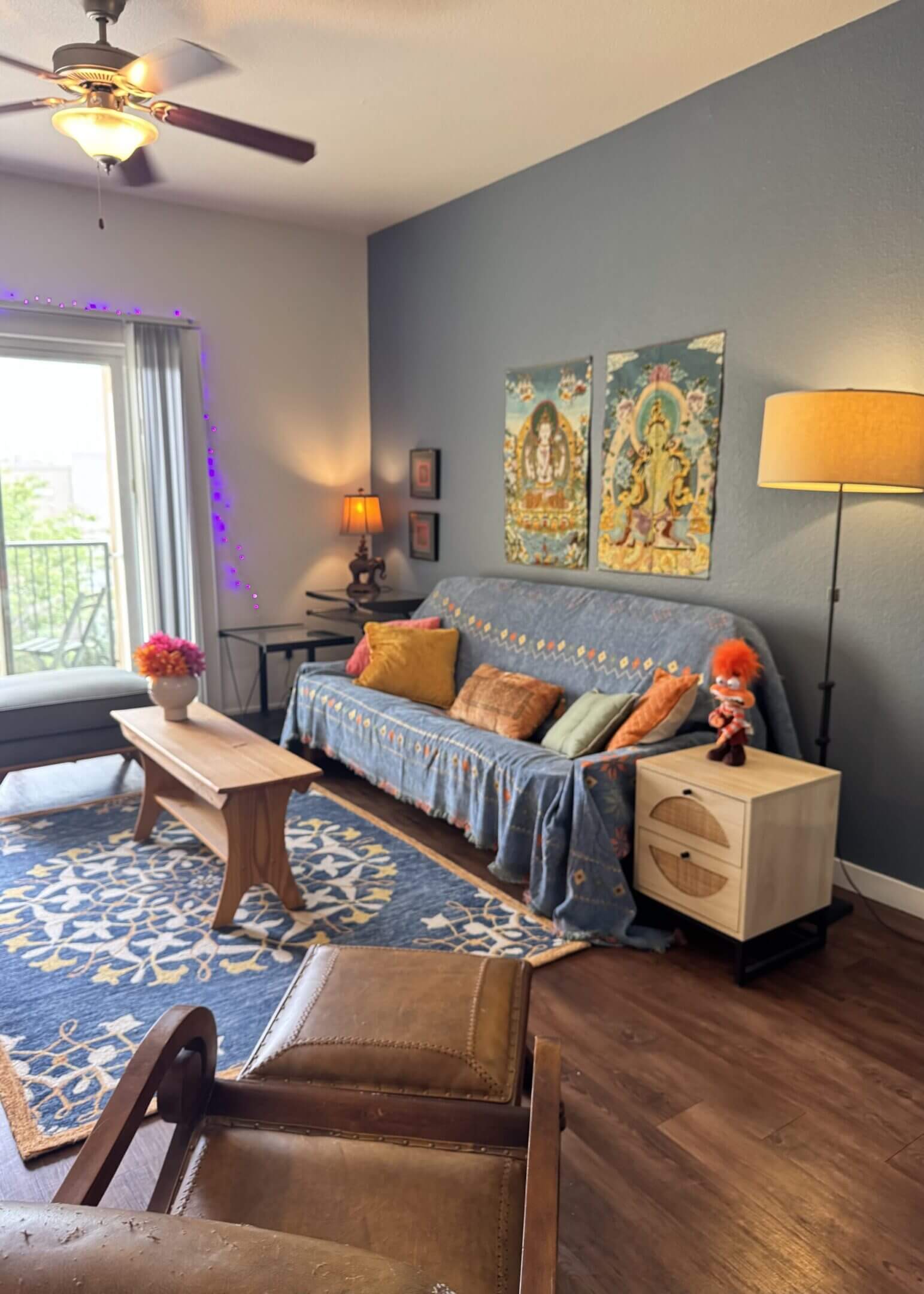 Cozy living room with a blue sofa, wooden coffee table, and colorful wall art.