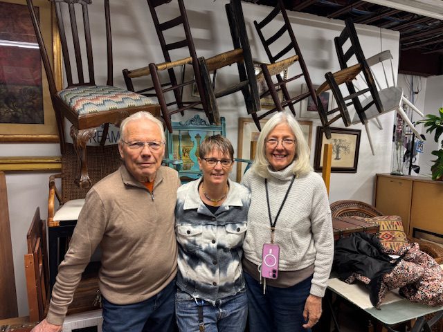 Three people in a room with chairs.